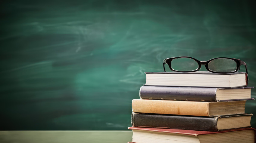 Books stacked neatly with glasses and pencils on a classroom chalkboard celebrating teachers day educational tools Books stacked neatly with glasses and pencils on a classroom chalkboard celebrating teachers day educational tools