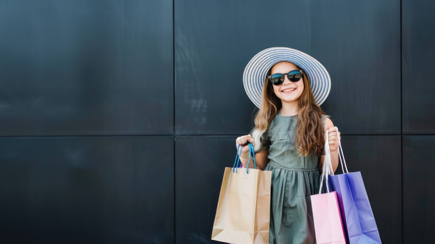 A young woman in sunglasses hat holds shopping bags against black background A young woman in sunglasses hat holds shopping bags against black background