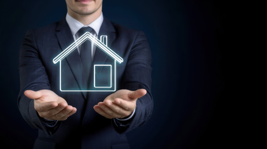 A businessman in a suit holding a glowing house icon on a dark blue background A businessman in a suit holding a glowing house icon on a dark blue background