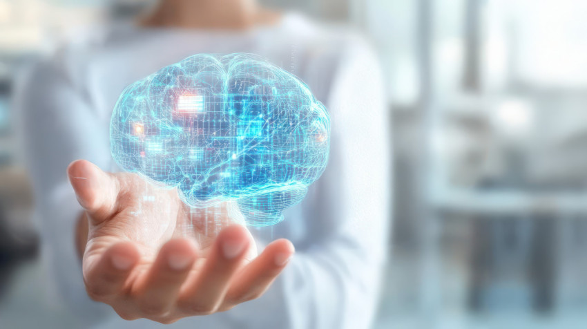 A person holds a virtual hologram of a digital brain with data connections in their hand against a blurred background