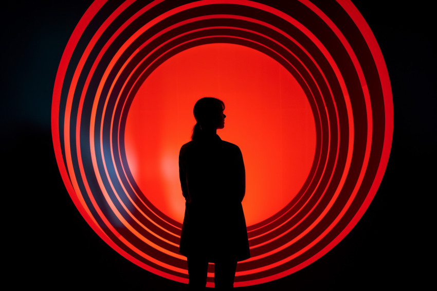 A woman outline can be seen against a round bright hole