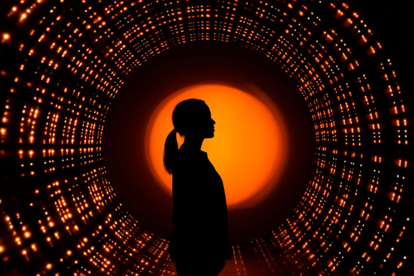 A woman outline can be seen against a round bright hole