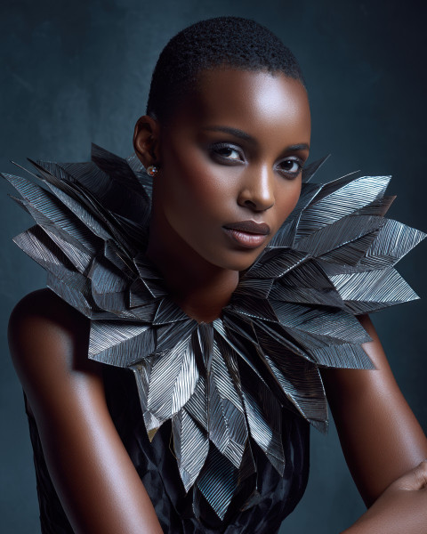 East African model in sculptural couture seated low