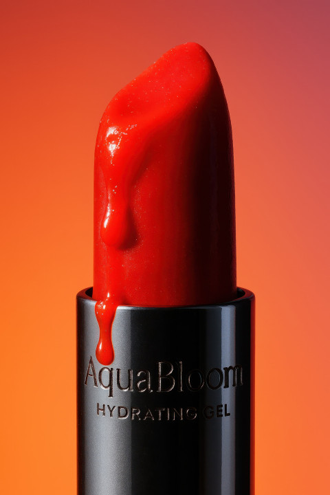 Red lipstick bullet melting at tip under hot light with silver base reflecting bold colors Red lipstick bullet melting at tip under hot light with silver base reflecting bold colors