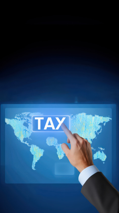 Businessman touches the word TAX on a screen with a global map Businessman touches the word TAX on a screen with a global map