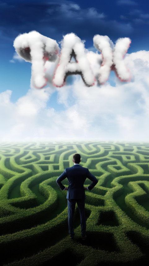 Businessman faces a maze with TAX text in the sky Businessman faces a maze with TAX text in the sky