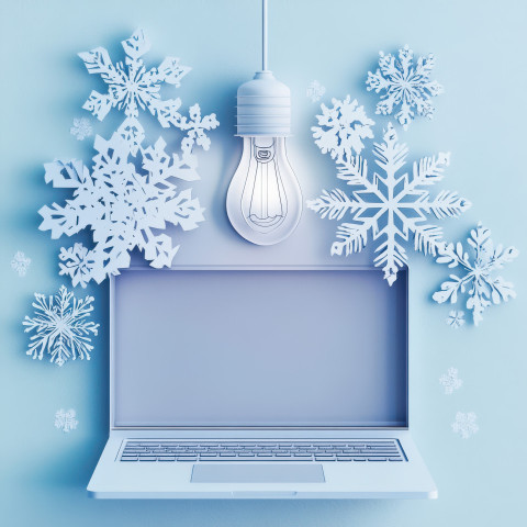 A laptop with a cutout lightbulb above it A laptop with a cutout lightbulb above it